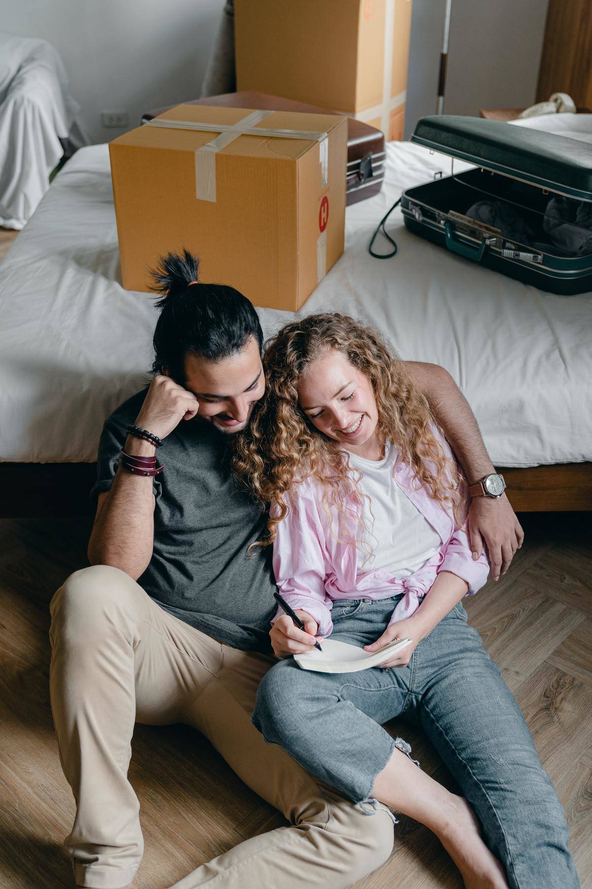Couple laughing sitting on floor writing on notebook
