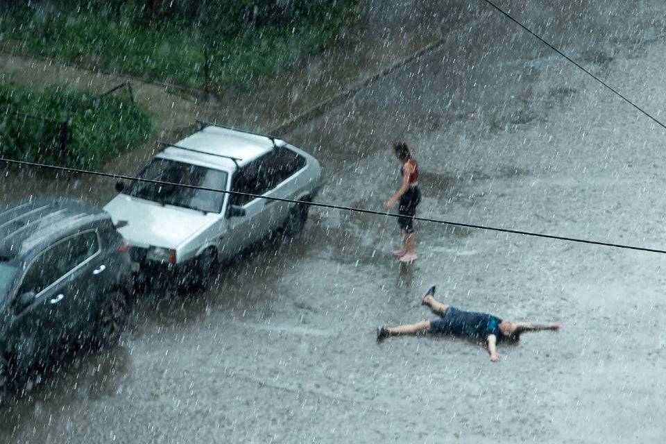 Man lying down on road in pouring rain