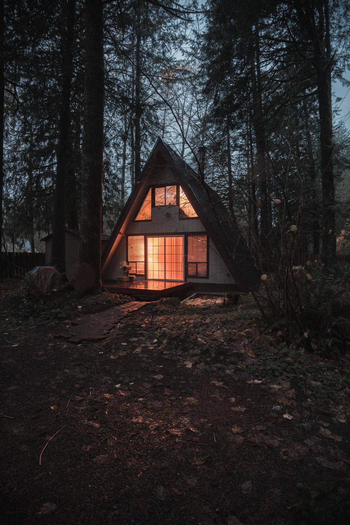 A-frame cottage glowing in woods