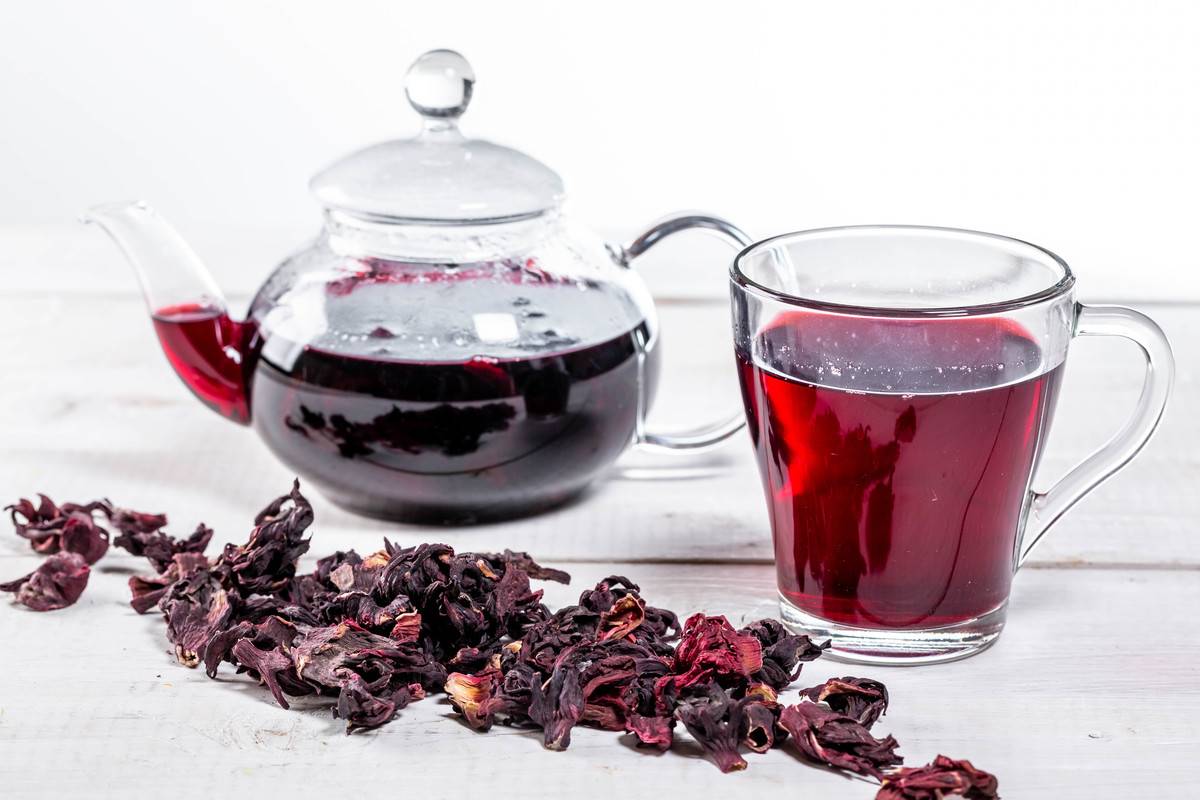 njm-pot Brewed hibiscus tea in a glass teapot and a Cup with dry hibiscus flowers