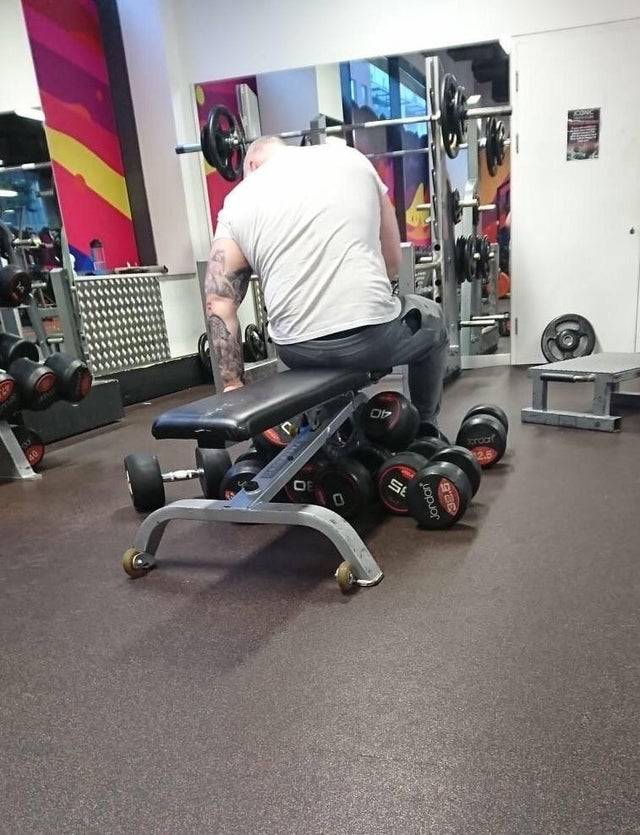 man hoarding weights at the gym