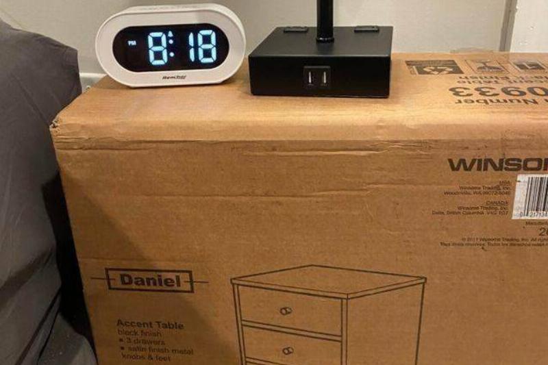 using box with unassembled nightstand as bedside table