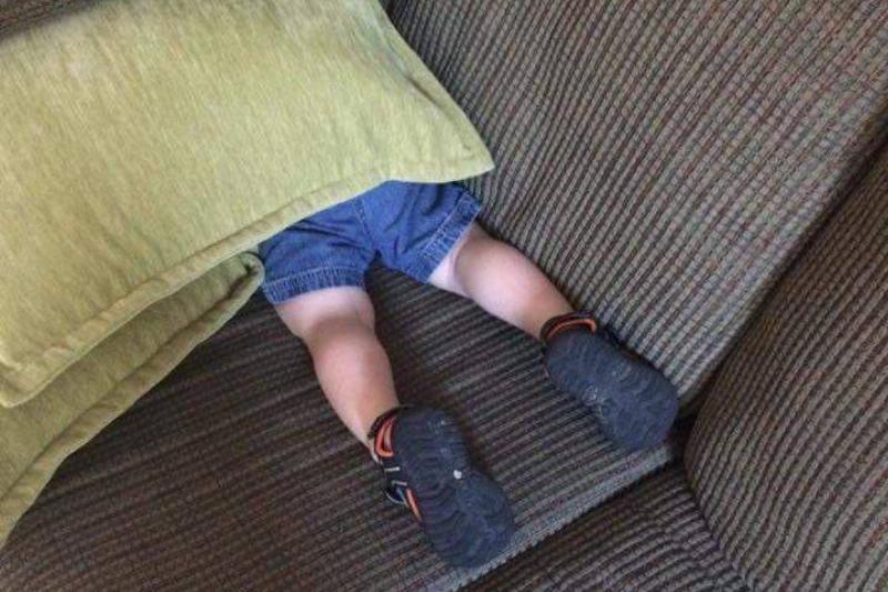 kid hiding under pillow with legs sticking out