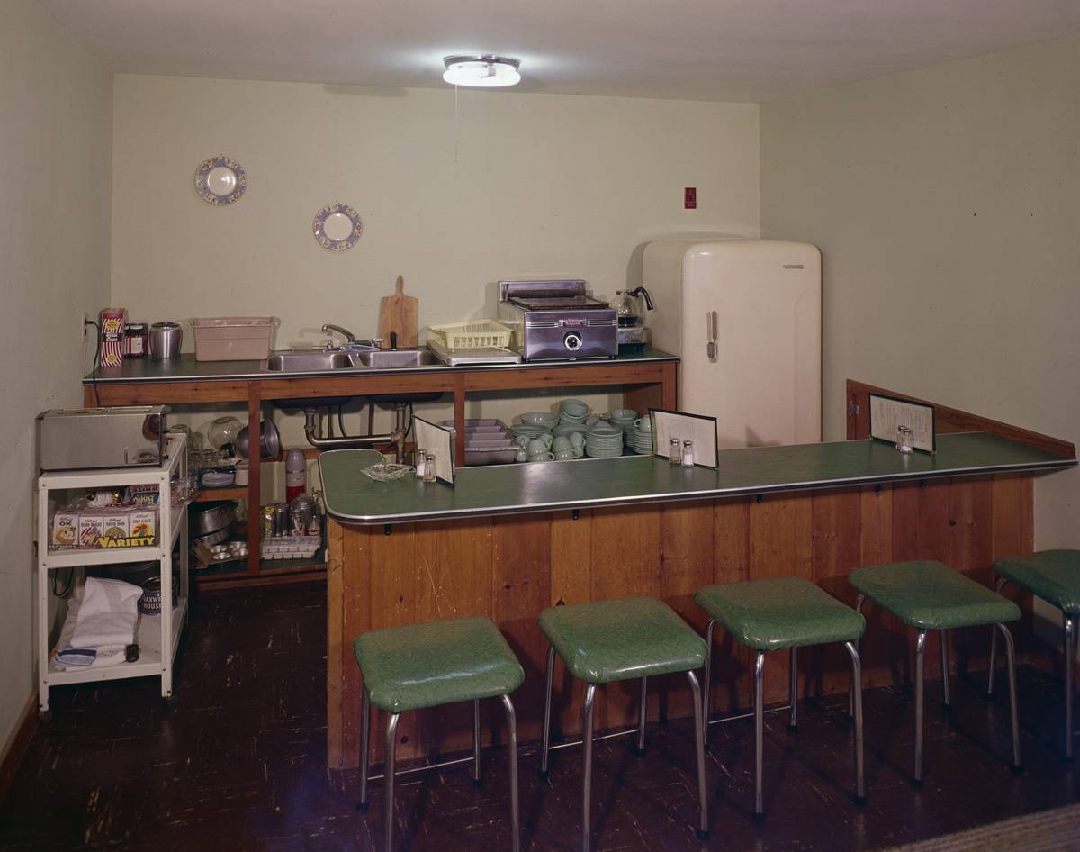 A 1960s kitchen with a bar has green laminate on the countertop.