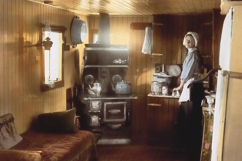 In this colorized photo from 1915, a woman stands in her small kitchen.
