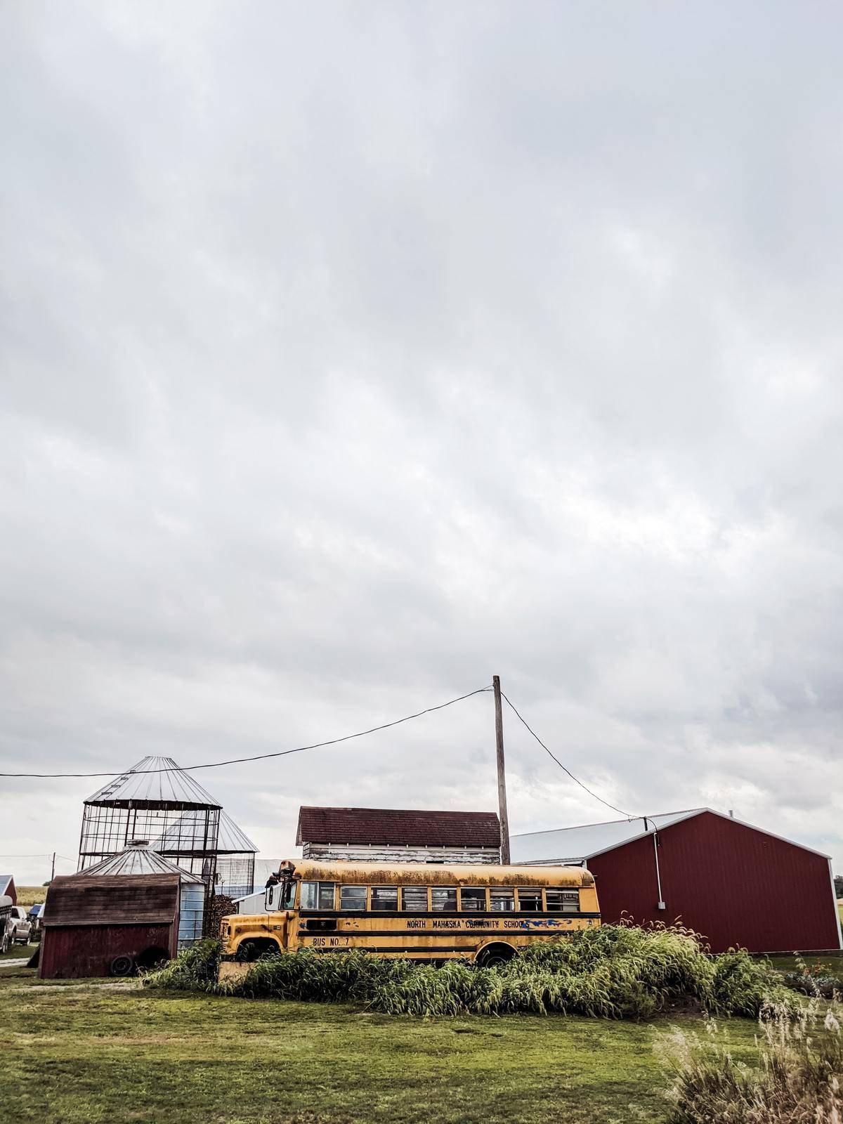 A dilapidated school bus sits in front of impoverished buildings in Kansas.