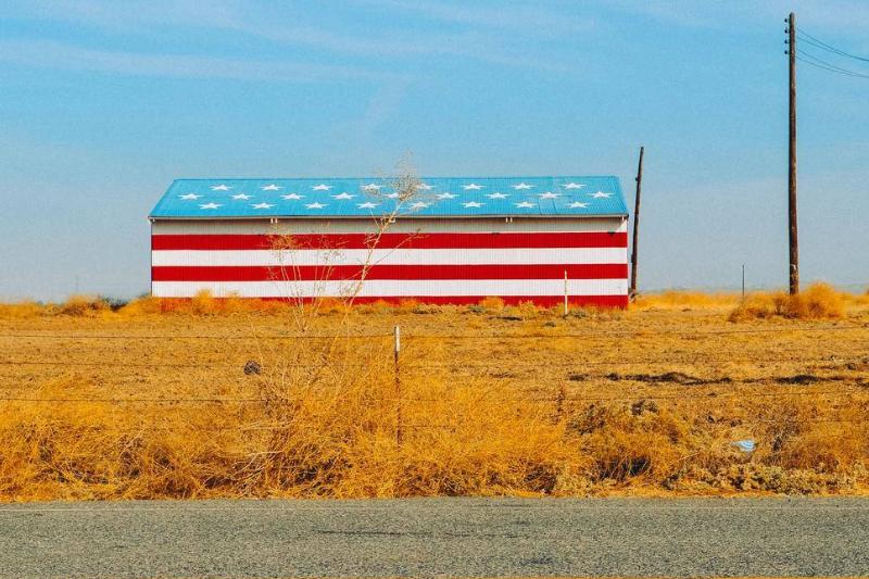 patriotic building An impoverished building in a field is painted with the American flag.