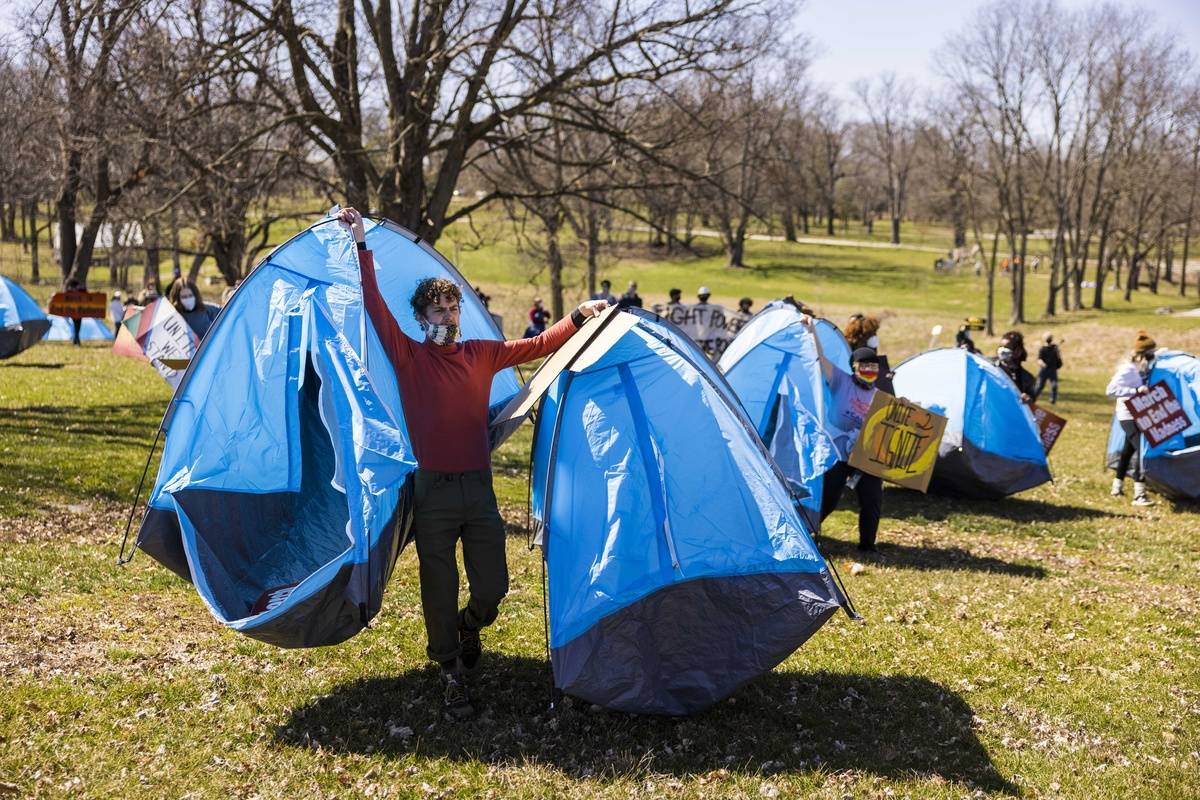 pitch tents Indiana residents carry tents onto a field to sleep overnight.