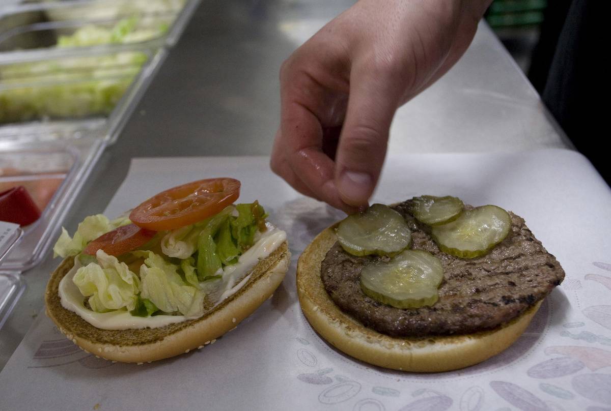 qec-pickles An employee places a pickle in a whopper burger at a Burger King restaurant in Basildon, U.K., on Wednesday, Sept. 8, 2010