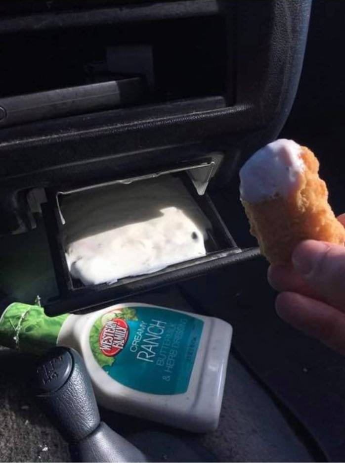 A person uses a drawer in their car as a ranch compartment.