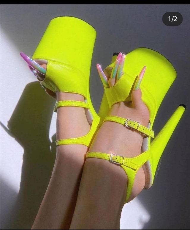 A woman wears yellow heels and long fake nails on her toenails.