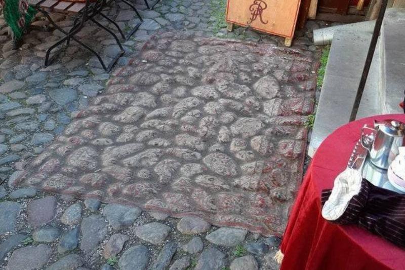 A rug laid over cobblestone is so worn down it appears to blend in with the stones