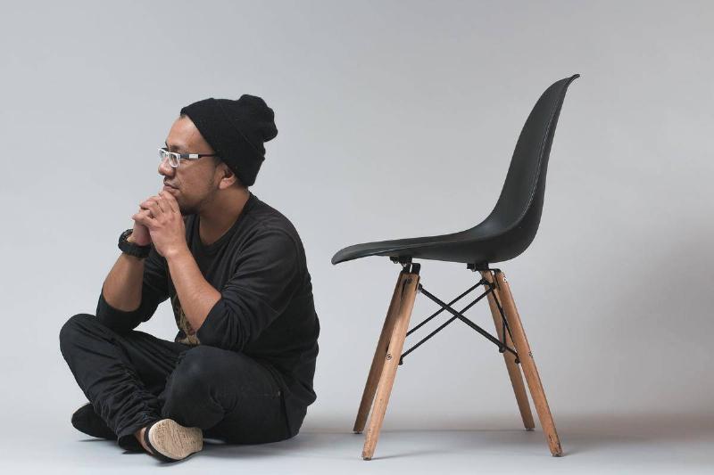 cross-legged a man sitting cross-legged next to a chair