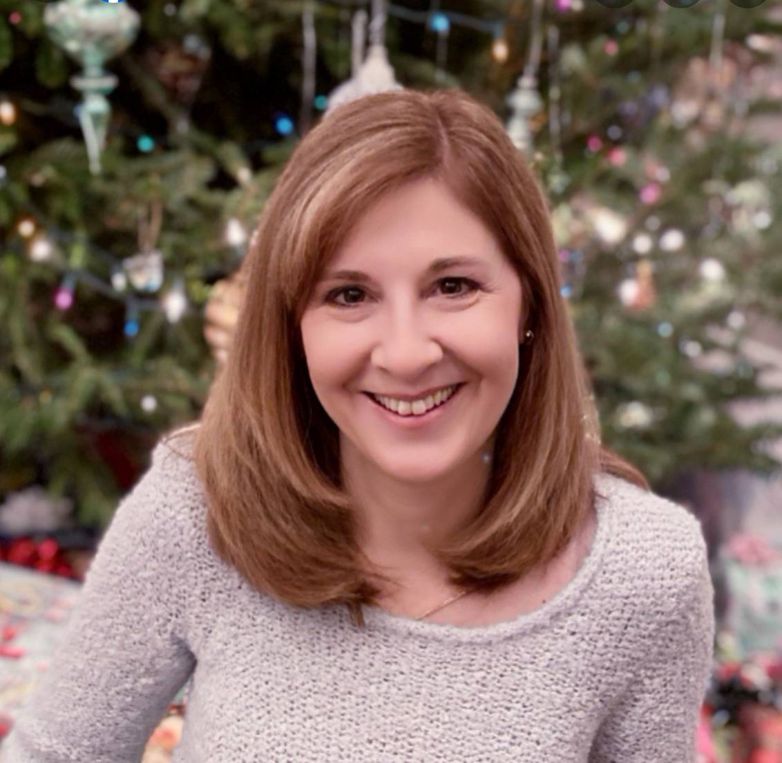 Jennifer Cartellone smiles for a photo in front of a Christmas tree.