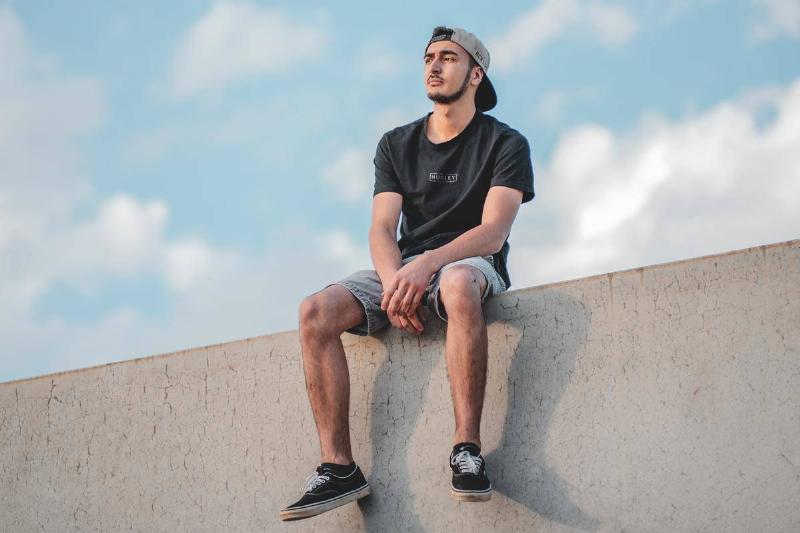 spread out a man sitting on a wall with legs spread out