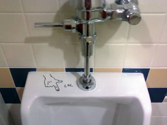 Public bathroom graffiti: a drawn hand pointing with its index finger and 