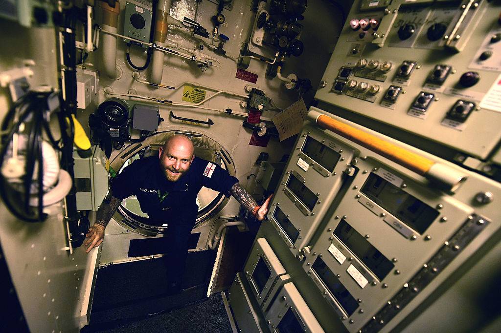 a crew worker walking through a submarine