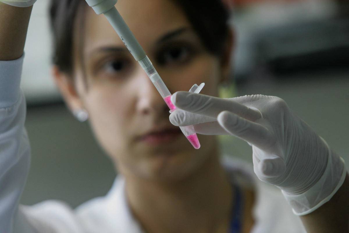 studying dna A woman holds up a dropper filled with dna samples to study.