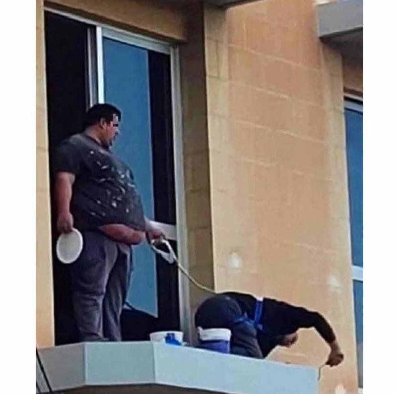 man holding guy on balcony attached with a leash