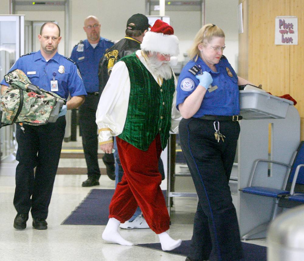 The TSA walks Santa over to another area of the security zone and looks at his belongings. 