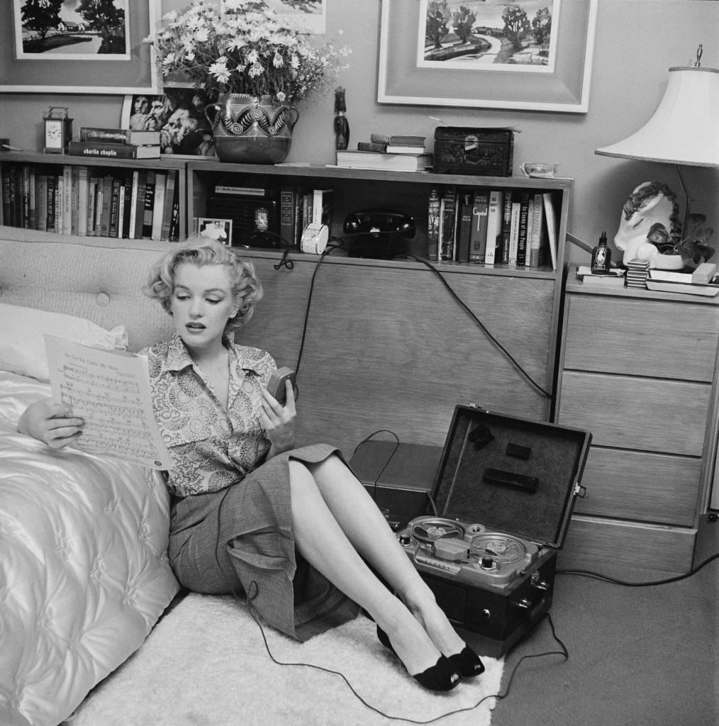 marilyn monroe reading sheet music while sitting on a bedroom floor with a tape player on the side