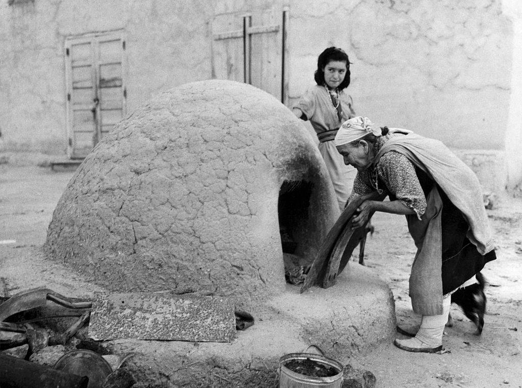old woman baking in mud oven
