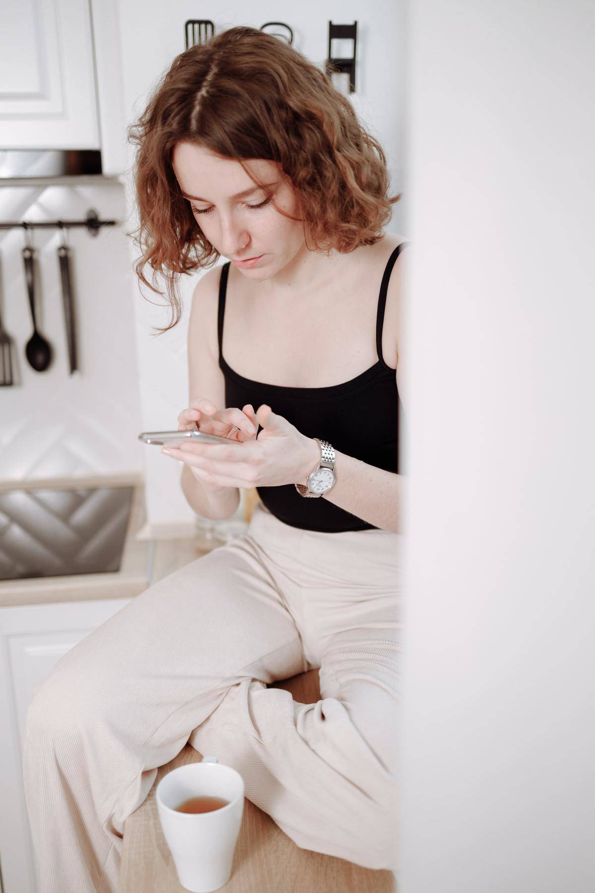 Woman on cell phone sitting on kitchen counter