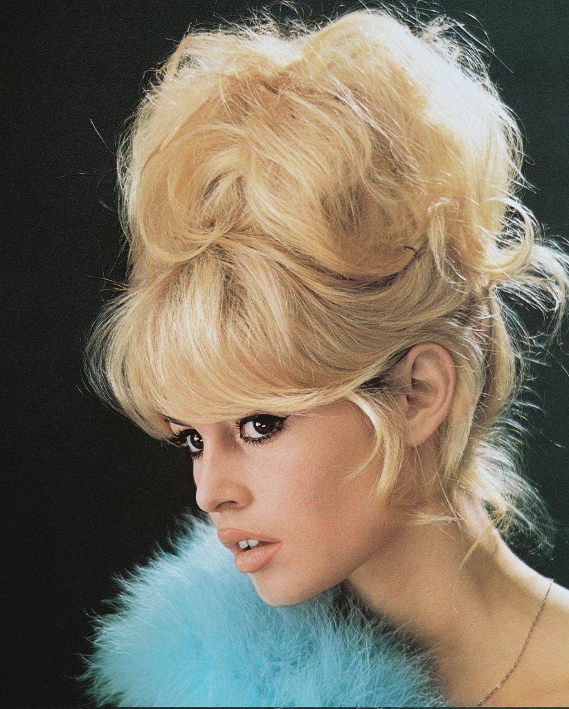 French actress, Brigitte Bardot, with a bouffant hairstyle and a blue boa, 1960