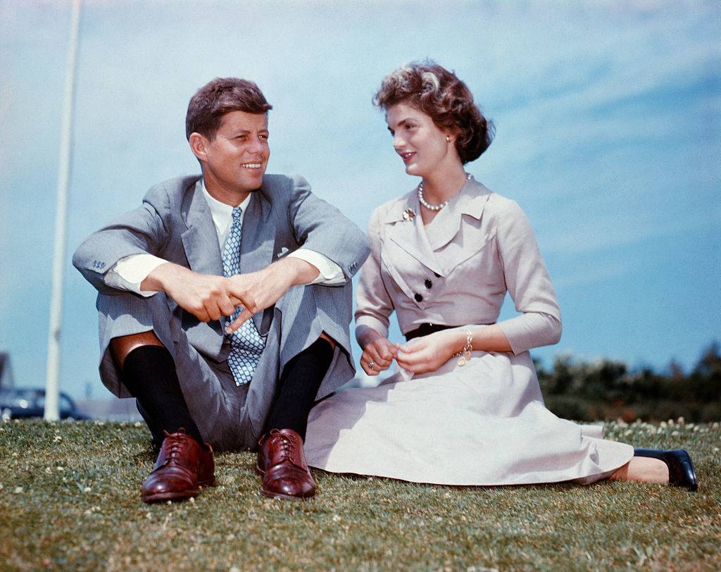 John F. Kennedy and Jacqueline Bouvier sit together in the sunshine