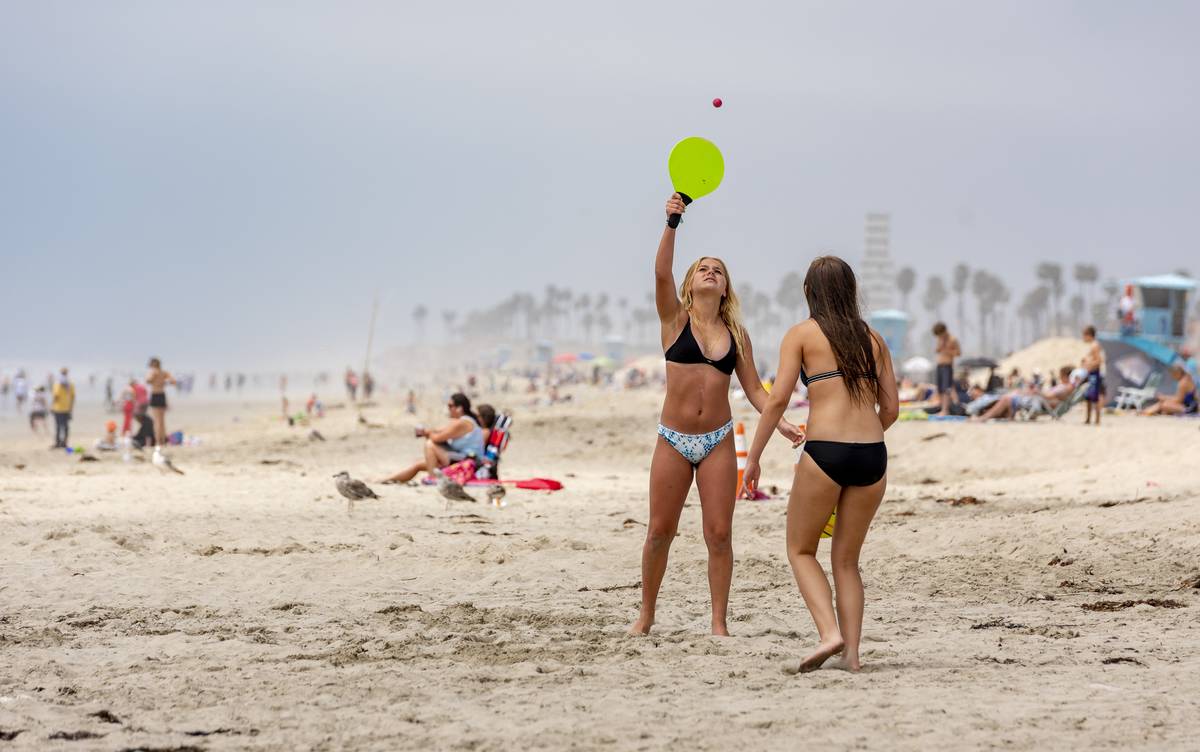 Women play paddle ball at SoCal beach near Huntington Beach pier