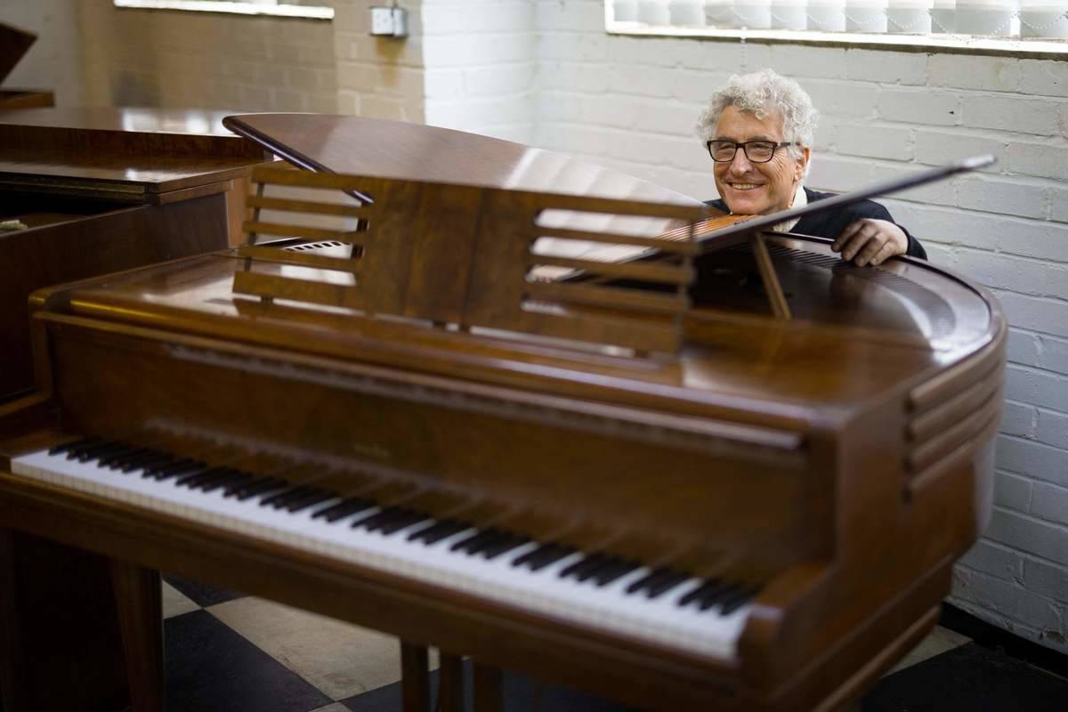 Royal piano restorer David Winston poses for a photograph with Wurlitzer 'Butterfly' Grand Piano, dated 1937, at his workshop in Biddenden in south-east England