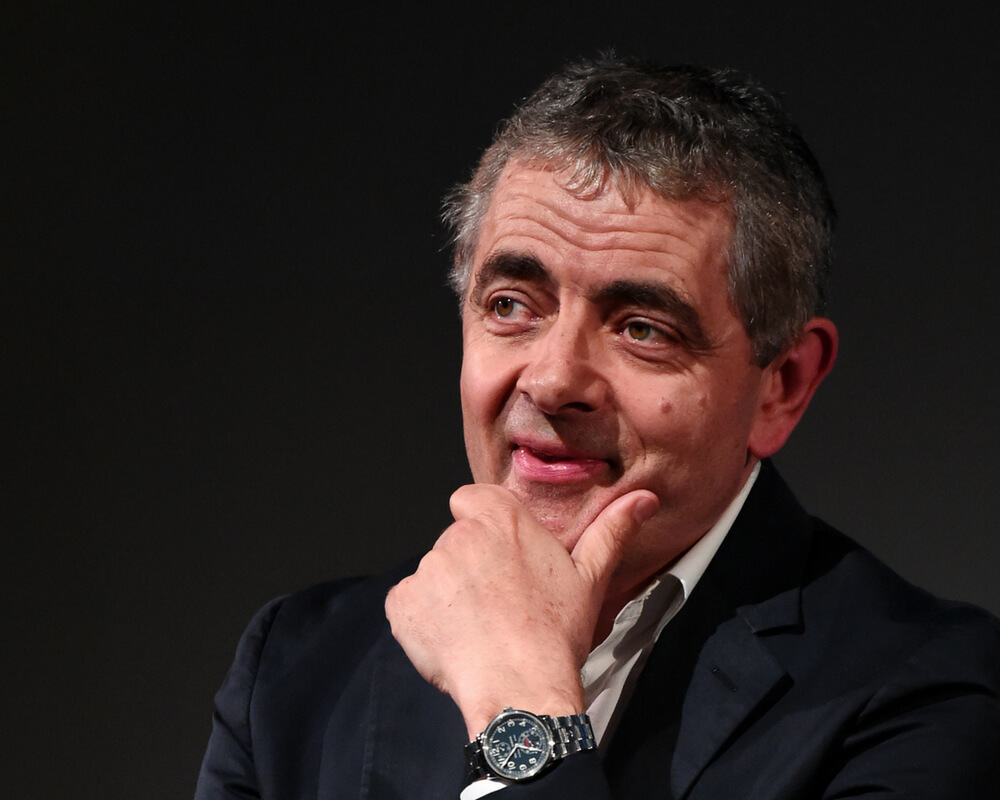 Rowan Atkinson with hand on chin thinking 