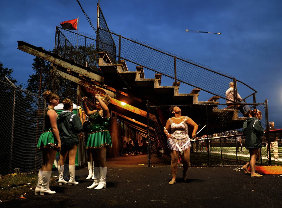 Students stand near school bleachers at a varsity sports game