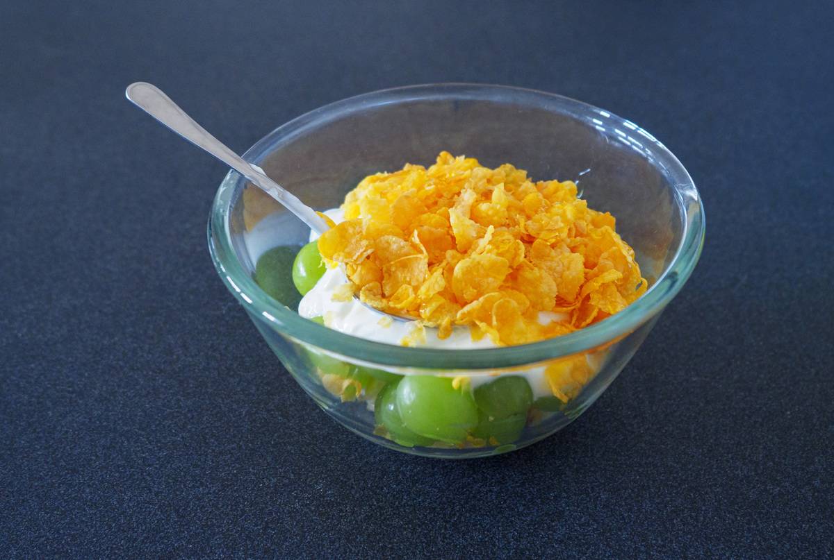 cereal A glass bowl of sugar-free cereal, yogurt and grapes on a table.