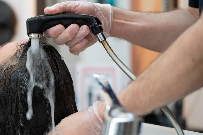  A hairdresser washes a customer's hair at a sink in a hair salon