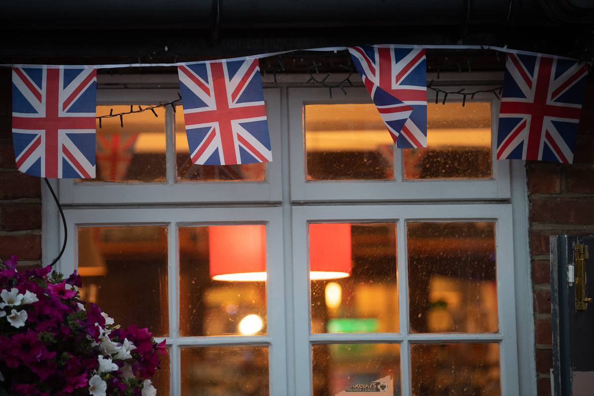 03 July 2022, Great Britain, London: Union Jack flags hang from the window of a pub. 