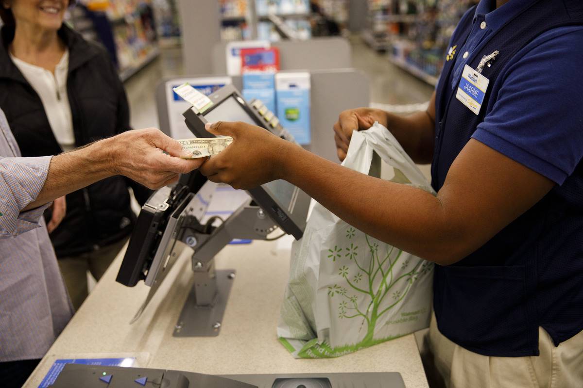 A customer hands cash to an employee while making a purchase at a Wal-Mart Stores Inc. location in Burbank, California, U.S., on Thursday, Nov. 16, 2017. Black Friday, the day after Thanksgiving, marks the traditional start to the U.S. holiday shopping season. Photographer: