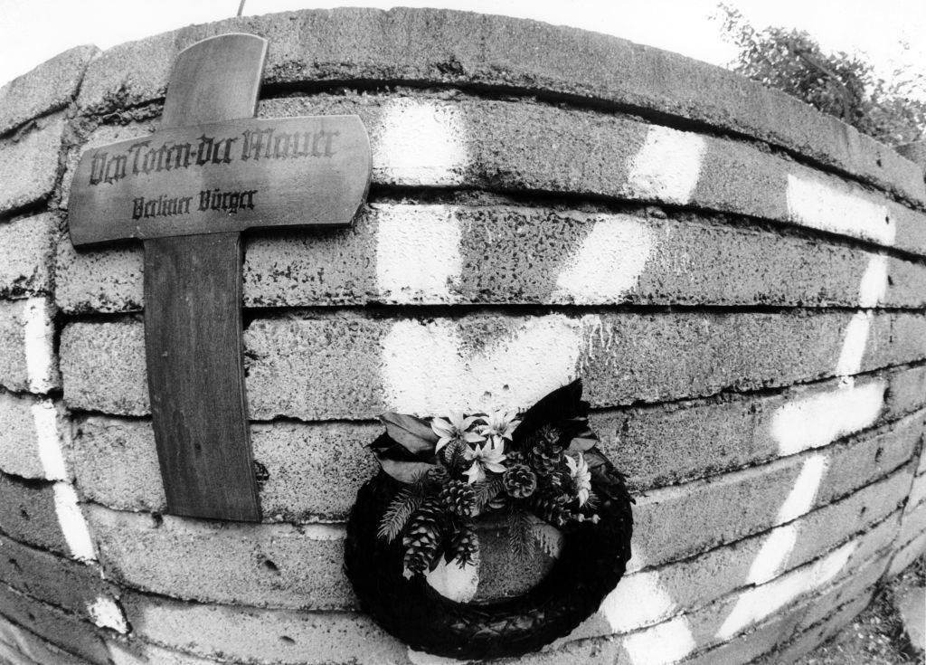 Mourners lay memorial cross/wreath