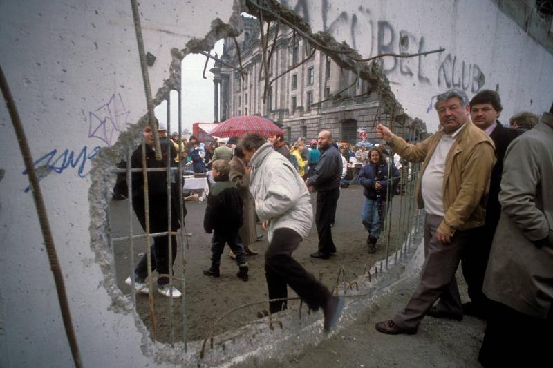 Germany / GDR, Berlin: The fall of the wall. People walking through a hole of the wall at Bernauer Strasse / Eberswalder Strasse.