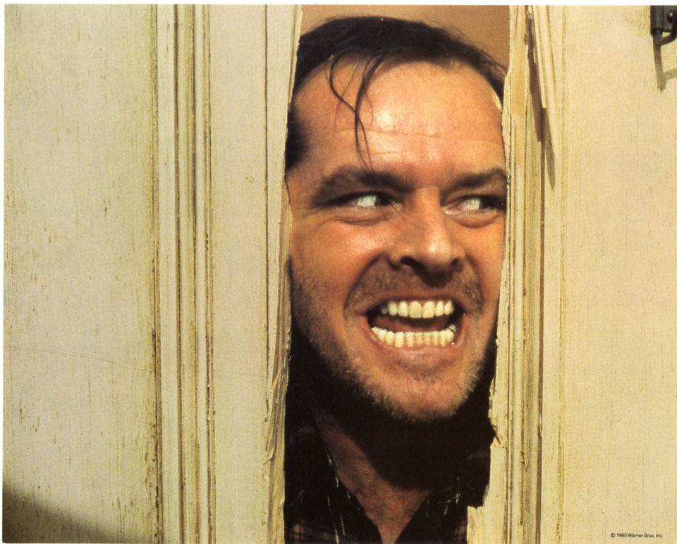 Jack Nicholson poking his face through a broken door as Jack Torrance in The Shining