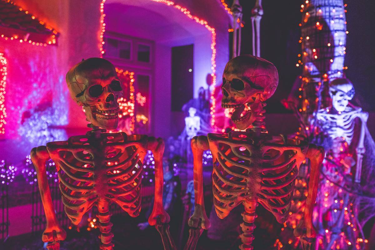 skeleton models standing in front of decorated house for Halloween