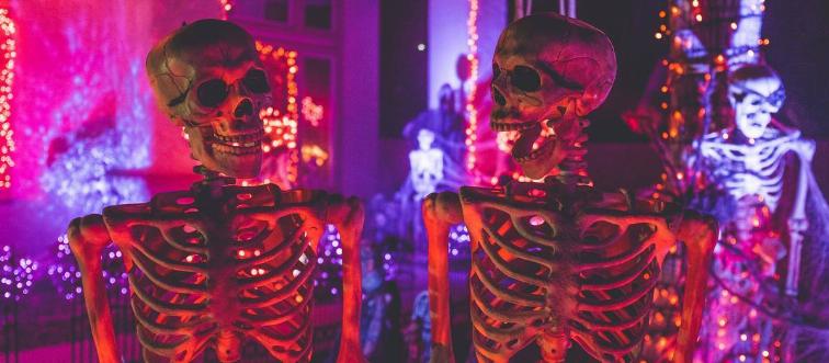 skeleton models standing in front of decorated house for Halloween