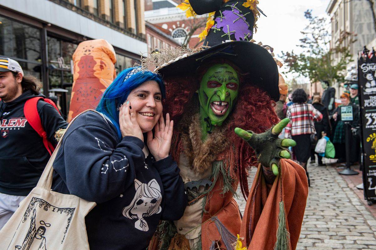 A costumed reveller dressed as a witch takes a photo with a fellow  reveller on Halloween in Salem, Massachusetts on October 31, 2022.