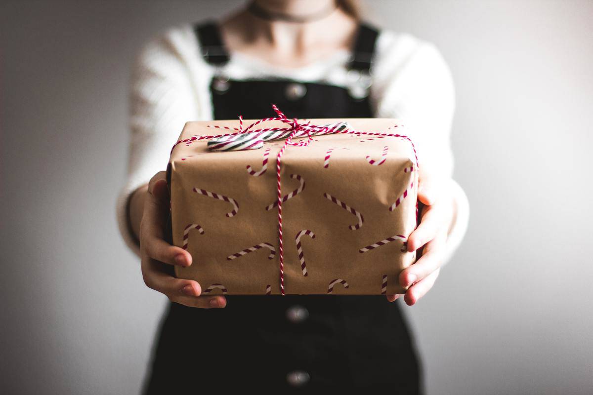 woman holding out present wrapped in candy cane paper