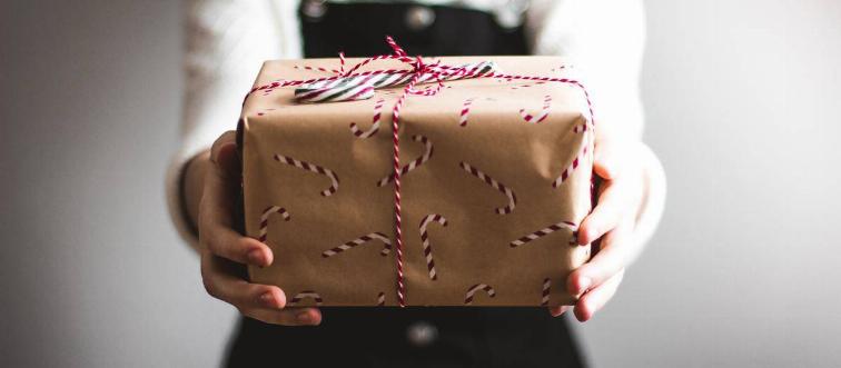 woman holding out present wrapped in candy cane paper