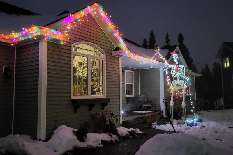 house with Christmas lights apparently being decorated by skeleton statue