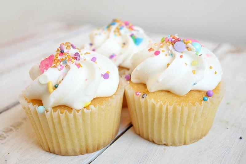 frosting cupcakes with vanilla frosting and colored sprinkles