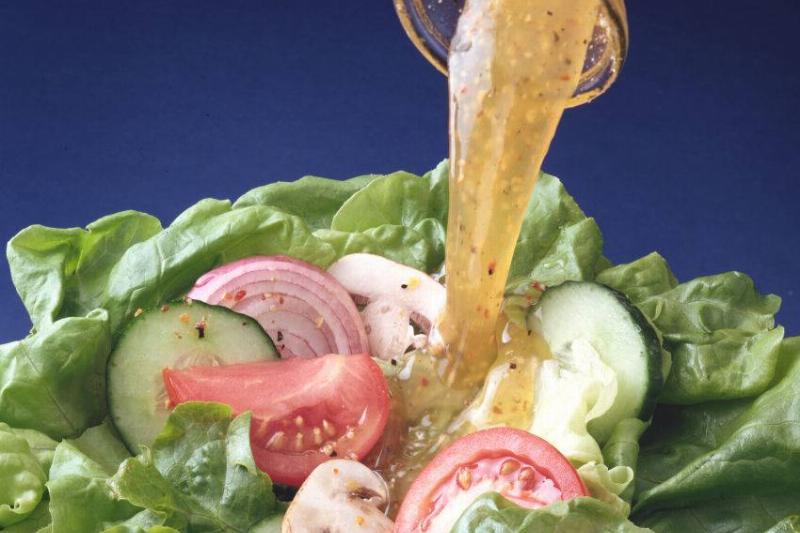 salad dressing 88048581 Close-up view of salad dressing getting poured onto a salad