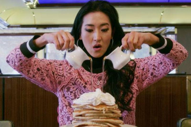 syrup 1124495125 woman pouring syrup onto a stack of pancakes