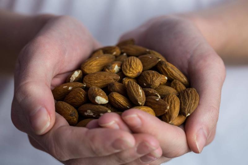 woman-showing-handful-of-almonds-in-close-up-2021-08-28-16-16-02-utc